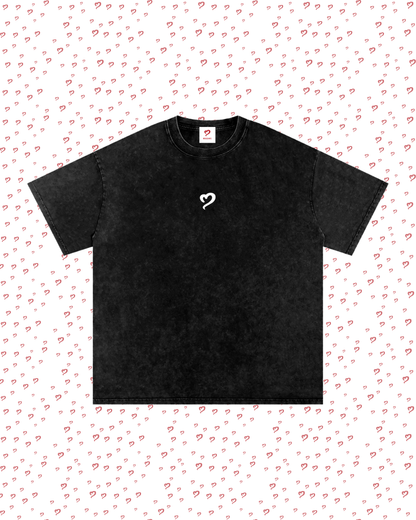 Black t-shirt with a white logo on a light pink background with heart patterns