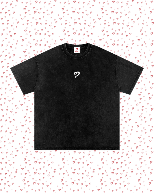 Black t-shirt with a white logo on a light pink background with heart patterns